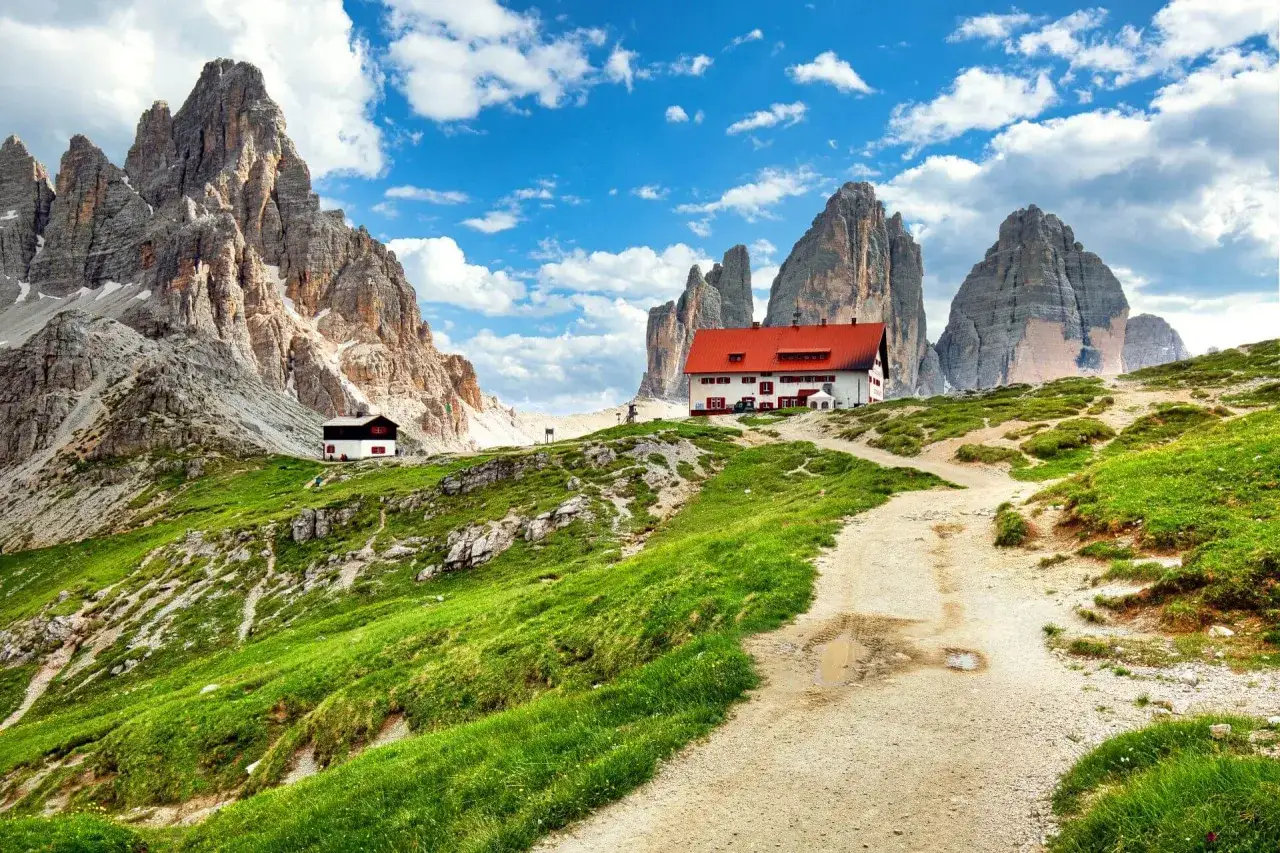 Rifugio alpino con tetto rosso e montagne imponenti sullo sfondo, un'idea perfetta per posti in montagna da visitare in giornata.