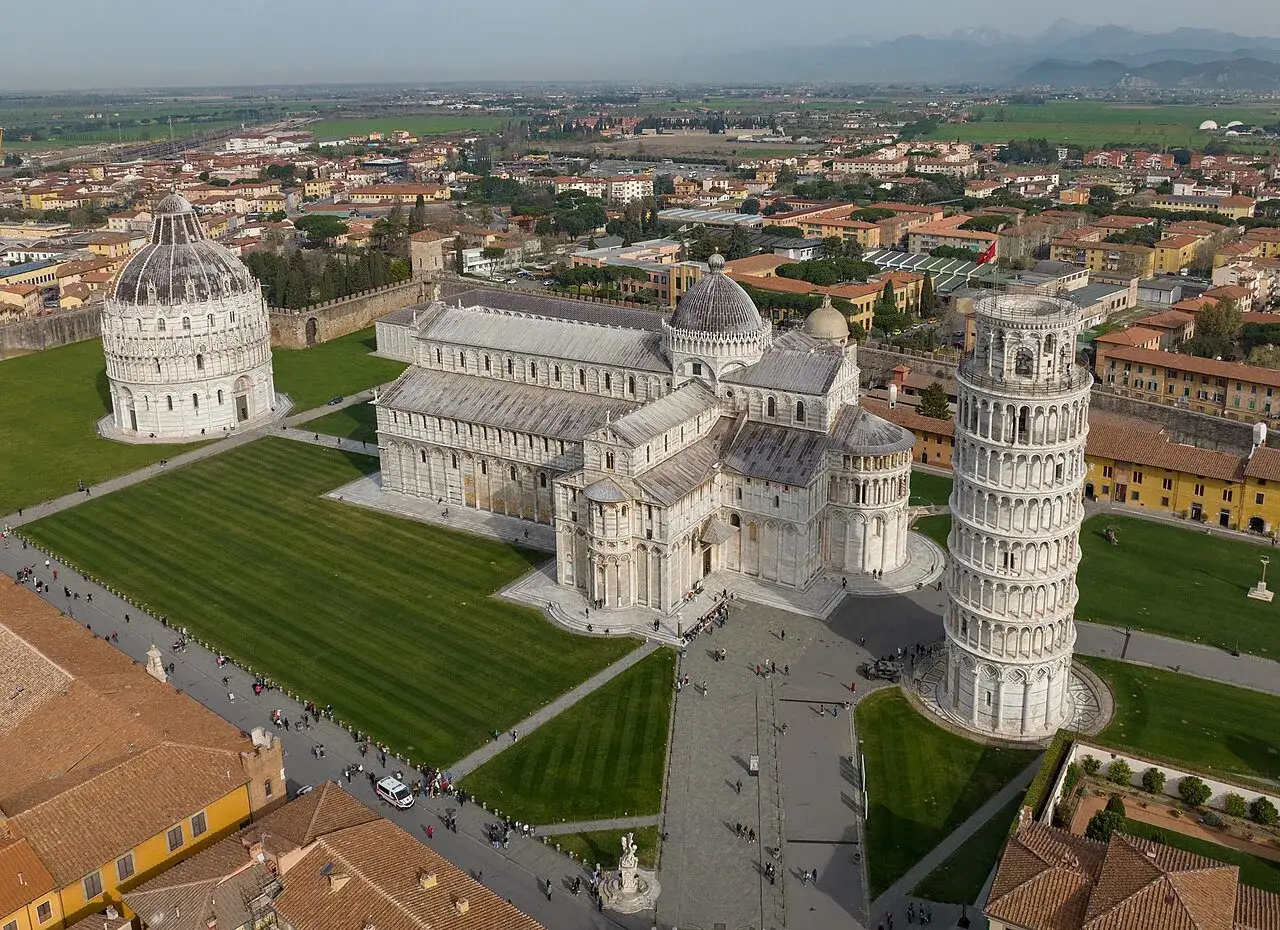 La celebre torre di Pisa, inclinata ma maestosa, domina la piazza con il Duomo e il Battistero.