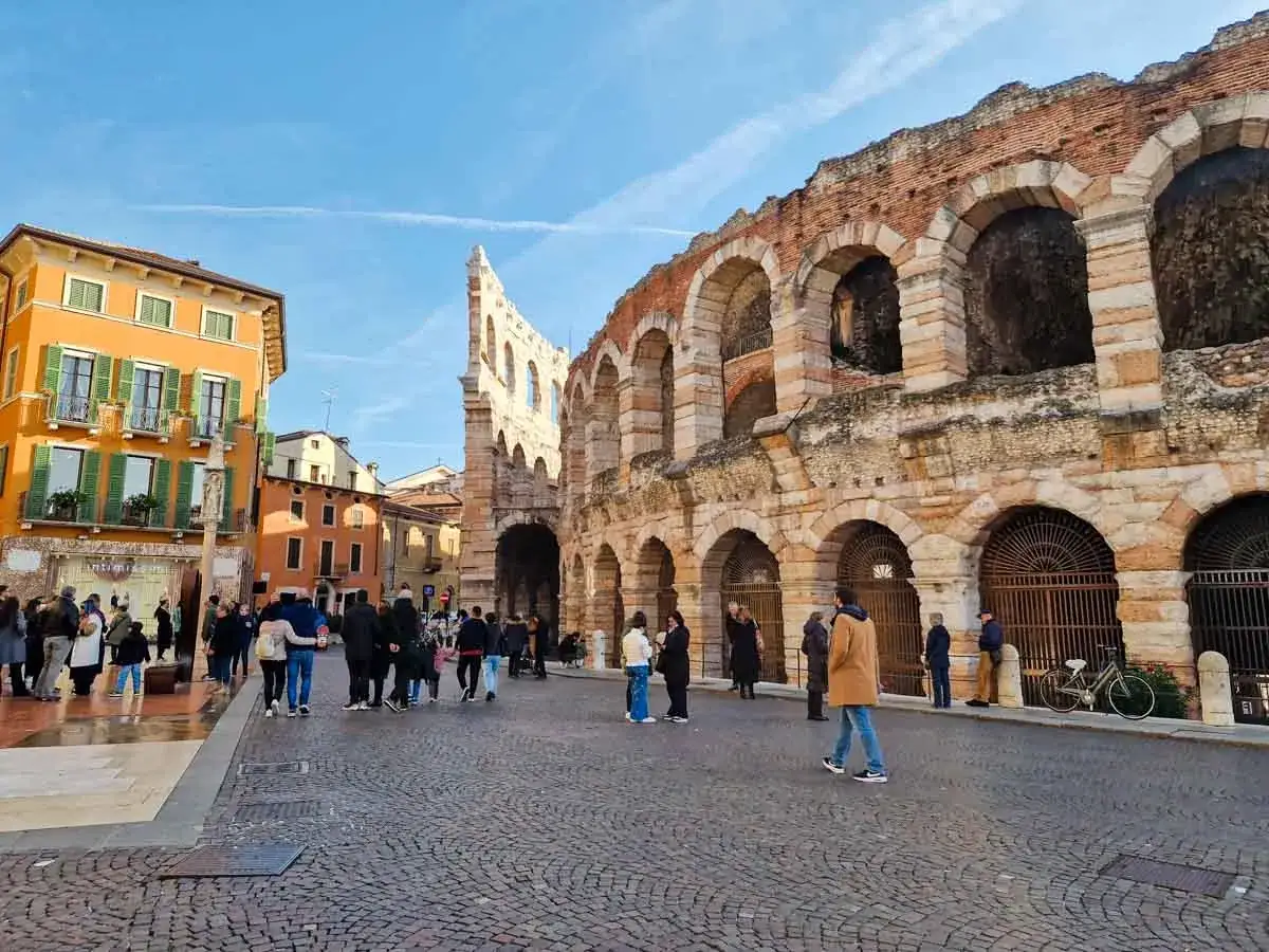 Arena di Verona, un'ottima idea per cosa vedere a Verona in 3 giorni. Turisti passeggiano nella piazza acciottolata.