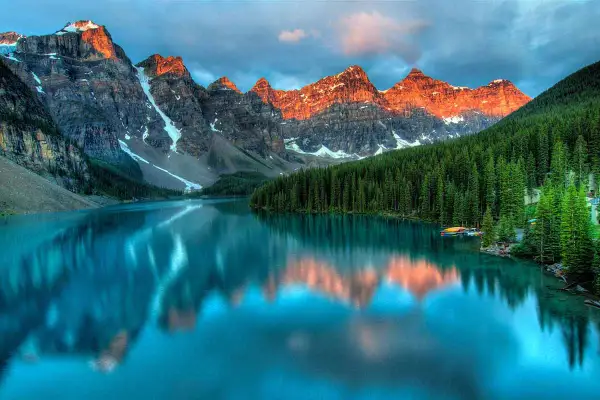 Lago turchese riflette le montagne italiane più famose, con foreste di conifere e cielo nuvoloso.