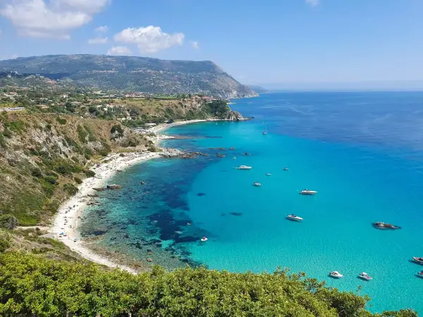 Spiaggia dorata, acque cristalline e barche all'orizzonte: ecco cosa fare in Calabria per una vacanza indimenticabile.