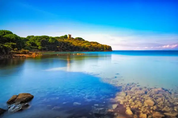 Torre medievale su una collina verdeggiante che si affaccia su acque cristalline, una delle punta ala spiagge più belle.