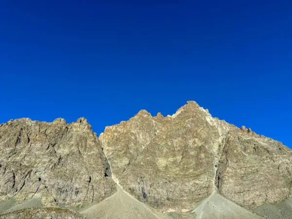 Cime rocciose del Monviso, con la via normale che sale verso la vetta sotto un cielo azzurro intenso.