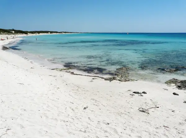 Spiagge Puglia Salento: sabbia bianca finissima, mare cristallino turchese e un velista all'orizzonte. Un paradiso naturale.
