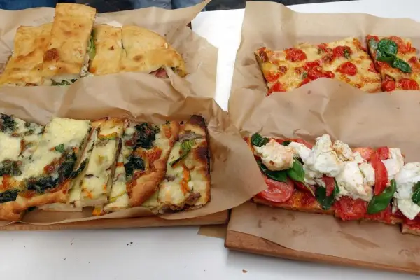 Pizza al taglio e focacce farcite, un'ottima idea per cosa mangiare a Roma. Diverse varietà con verdure, pomodoro e mozzarella.