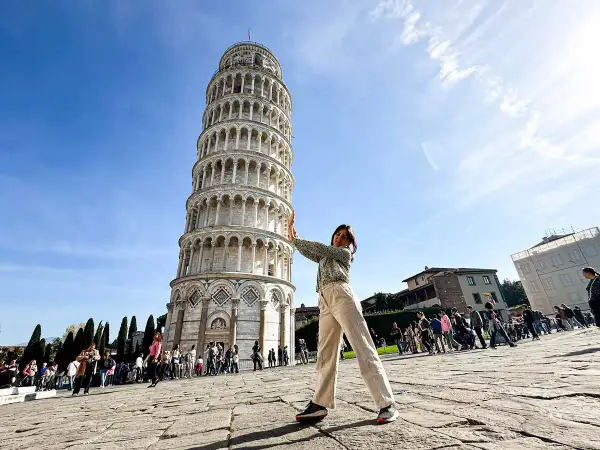 Ragazza fa finta di sorreggere la torre di Pisa, icona mondiale.