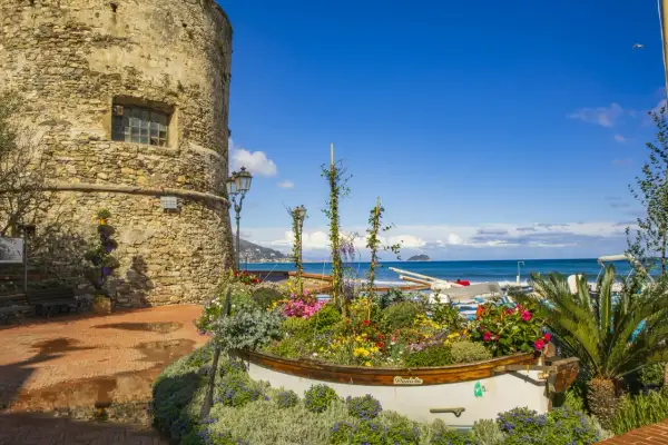 Laigueglia centro storico: torre medievale, barca fiorita e mare blu.