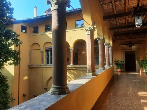Portico con colonne e archi, tipico della casa di Lucio dalla a Bologna. Luce solare illumina il pavimento lucido.
