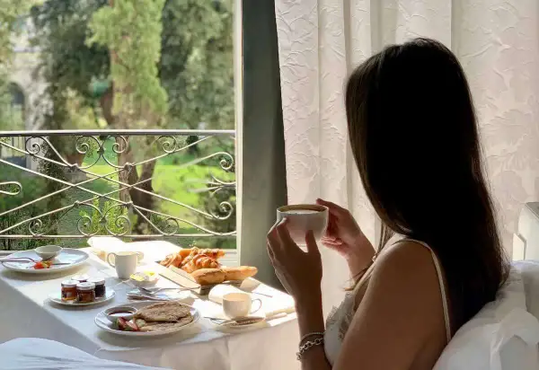 Colazione in camera a Roma: croissant, pancake e caffè con vista sul verde. Un'ottima opzione per sapere dove dormire a Roma.