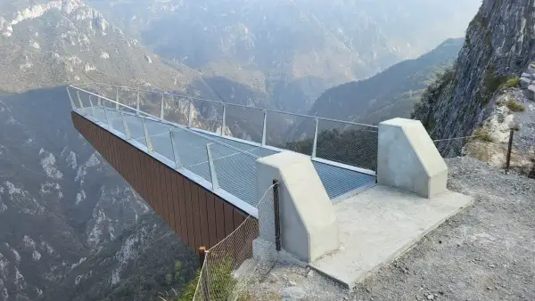 La passerella panoramica "Becco di Dossena" si protende su un profondo canyon, offrendo una vista mozzafiato sulle montagne circostanti.