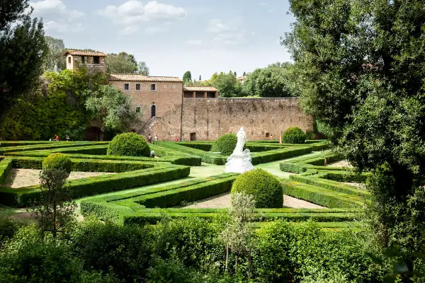 Giardini all'italiana con siepi geometriche e una statua, un assaggio di cosa vedere a San Quirico d'Orcia.
