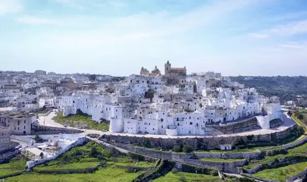 Panoramica di uno dei borghi medievali in Puglia, con case bianche a picco sul mare e un cielo azzurro.