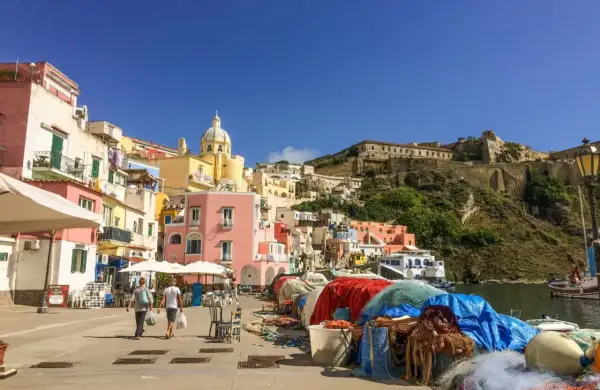 Colorate case a picco sul mare, un porto con reti da pesca e la fortezza in collina: ecco cosa vedere a Procida, un gioiello italiano.