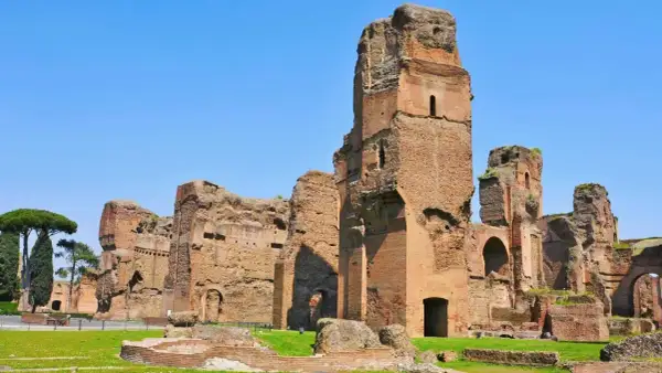 Imponenti rovine delle terme di Caracalla a Roma, con torri di mattoni che si ergono contro il cielo azzurro.