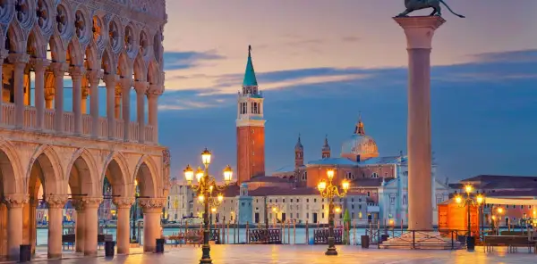 Piazza San Marco Venezia al tramonto, con il Palazzo Ducale, il Campanile e la Basilica di San Giorgio Maggiore illuminati.