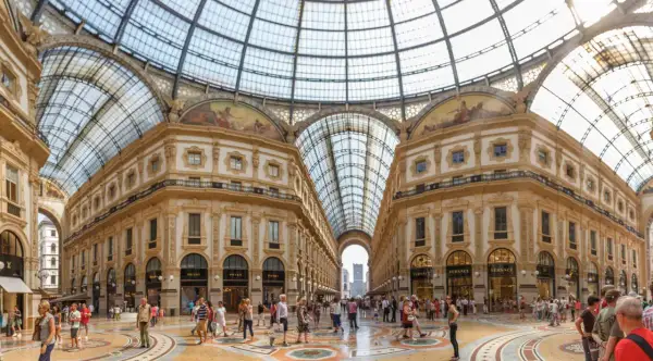 La Galleria Vittorio Emanuele II, un capolavoro architettonico con vetrate luminose e negozi di lusso, accoglie visitatori a Milano.