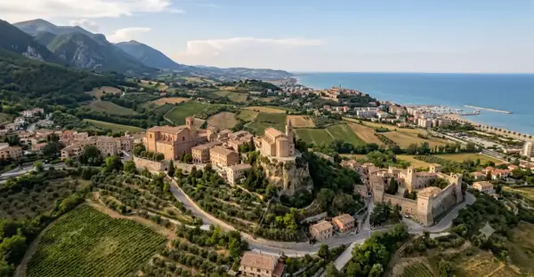 Borghi da visitare vicino Ascoli Piceno: un castello medievale e chiese storiche su colline verdi, con il mare all'orizzonte.
