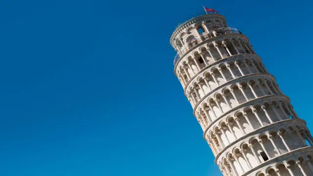 La Torre di Pisa dritta, un'icona architettonica con arcate eleganti, si staglia contro un cielo azzurro intenso.